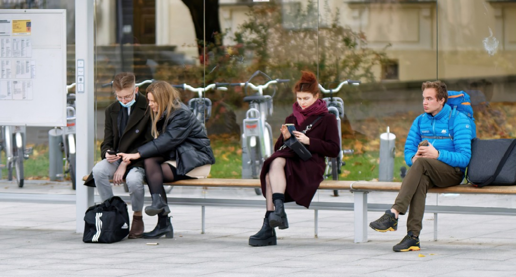 Bushaltestelle, junge Personen mit Smartphones